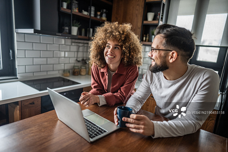 快乐的情侣在家使用笔记本电脑图片素材