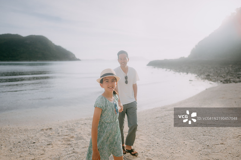 年轻女儿在海滩上牵着父亲的手图片素材