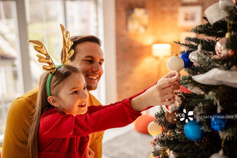 父亲在家中与女儿一起欢快地庆祝圣诞节图片素材