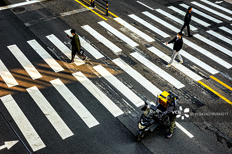 行人和送货骑手在斑马线处图片素材