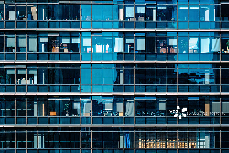 现代商业办公大楼，玻璃外立面，位于中央商务区。商务人士在白天的办公大楼内工作和开会。图片素材