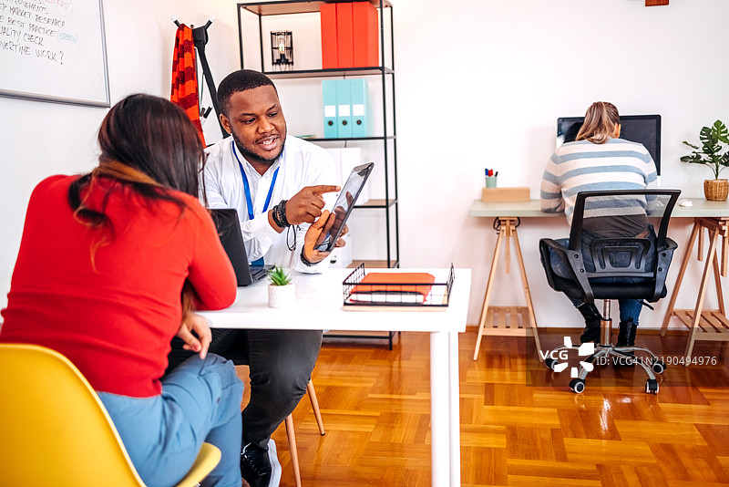 年轻的黑人男性在保险公司办公室与客户进行轻松的对话，提供建议。图片素材
