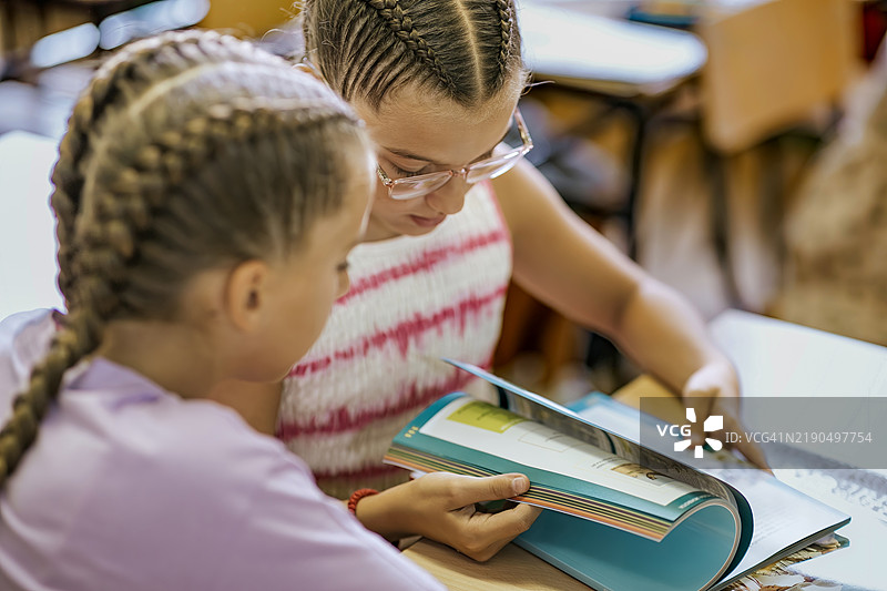 两个孩子在阳光明媚的下午一起在教室里阅读书籍图片素材