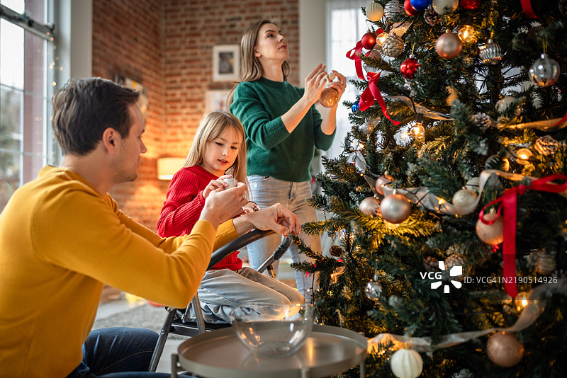 家庭在假日季节一起装饰圣诞树图片素材