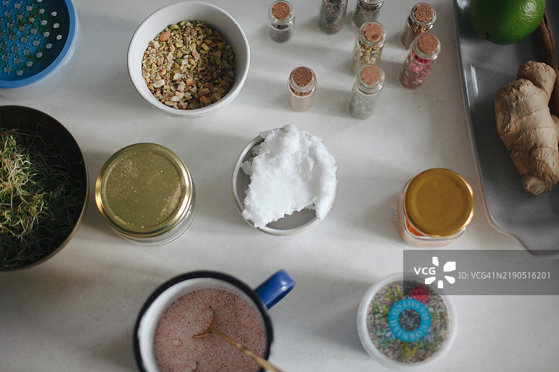 白色桌子的俯视图，上面有香料罐、盐和椰子油，烹饪所需的食材图片素材