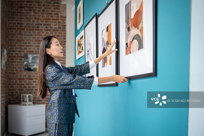 策展人在现代艺术画廊展览中布置装裱艺术作品图片素材