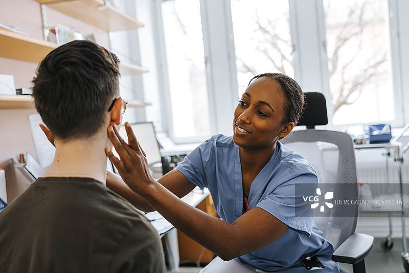 微笑的女性医疗专业人员在医院的诊所检查患者的淋巴结图片素材