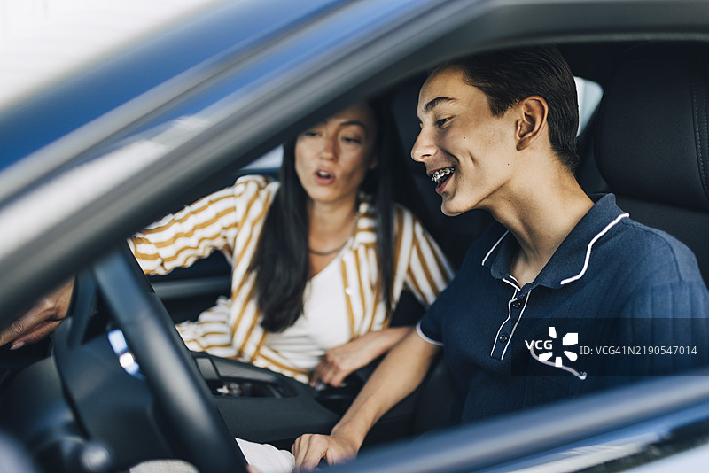 快乐的少年在车里接受母亲的驾驶课程图片素材