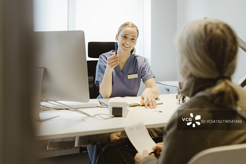 女医生在诊所的桌子旁与老年患者交谈图片素材
