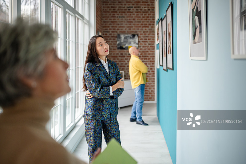 策展人和参观者在现代画廊环境中欣赏艺术展览。图片素材