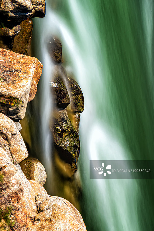 瀑布从崎岖的岩石上倾泻而下，形状像一个人脸面具图片素材