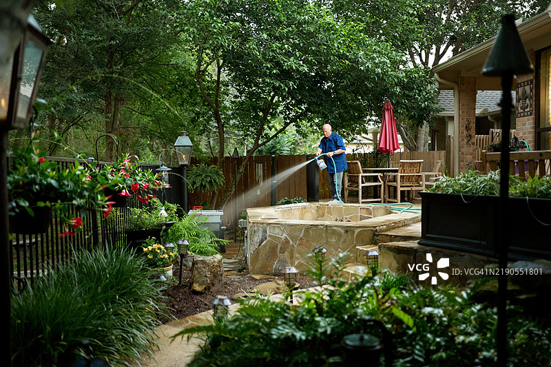 老年男子在后院用清洁剂和水管喷洒灭虫剂图片素材