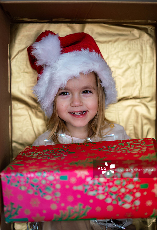 女孩向镜头展示她收到的礼物，她很喜欢并感到快乐。图片素材