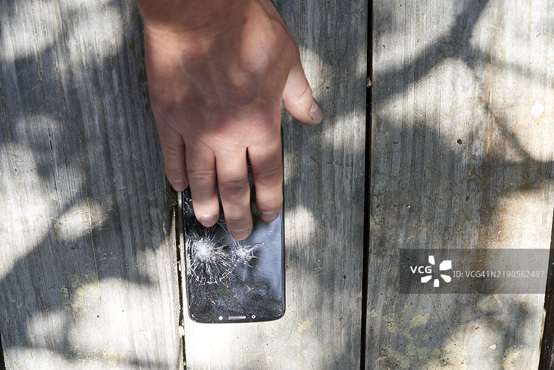 工人将损坏的智能手机放在木桌上图片素材