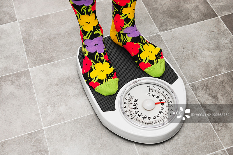 在浴室秤上称重的偏瘦女性，正在进行减肥。图片素材