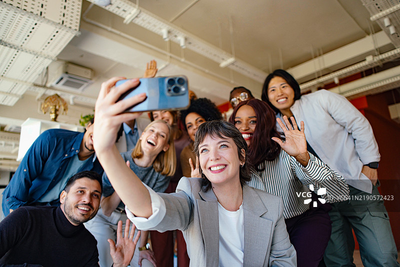 多元化的专业人士在现代办公室微笑并自拍图片素材