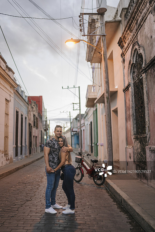 年轻的游客情侣在古巴卡马圭的鹅卵石街道上相拥图片素材