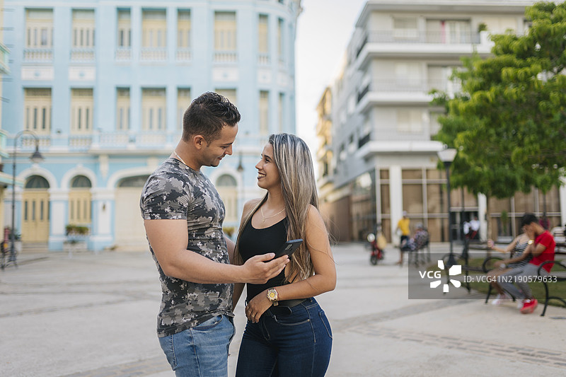 年轻游客情侣在古巴卡马圭查看智能手机图片素材