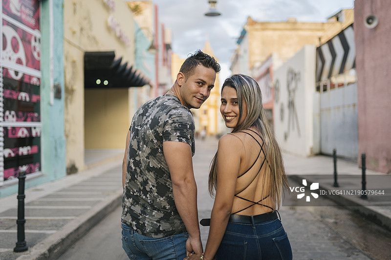 年轻游客情侣在古巴卡马圭手牵手漫步图片素材