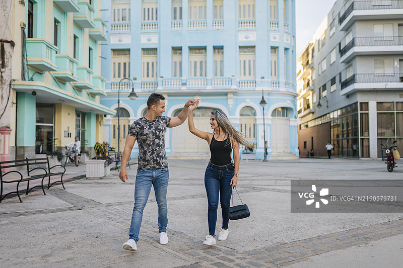 年轻情侣在古巴卡马圭手牵手跳舞图片素材