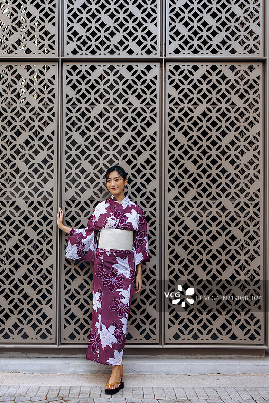 穿着紫色和服的女性站在装饰墙前图片素材