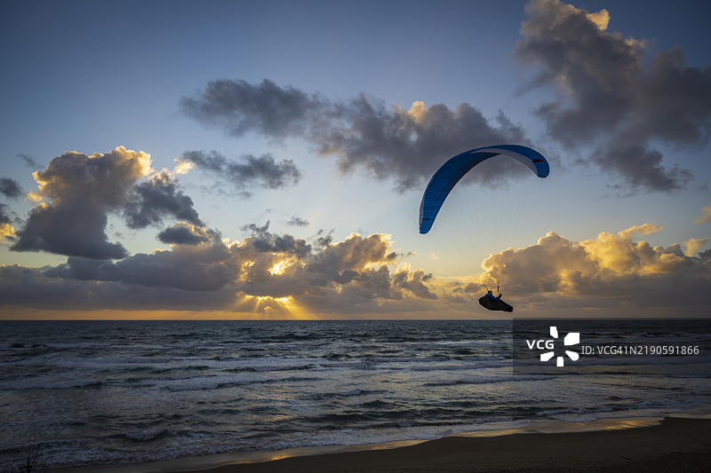 海面上空滑翔伞飞行者的剪影与天空相映图片素材