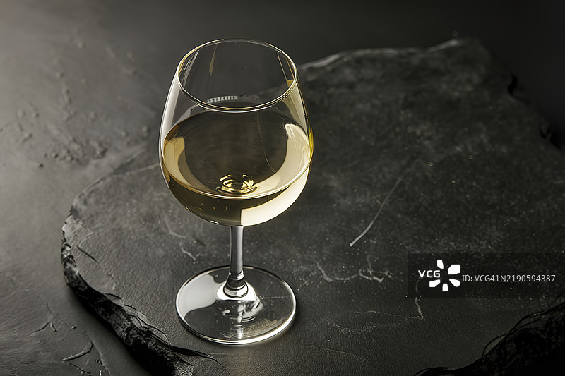 一杯白葡萄酒放在黑色石材背景上图片素材