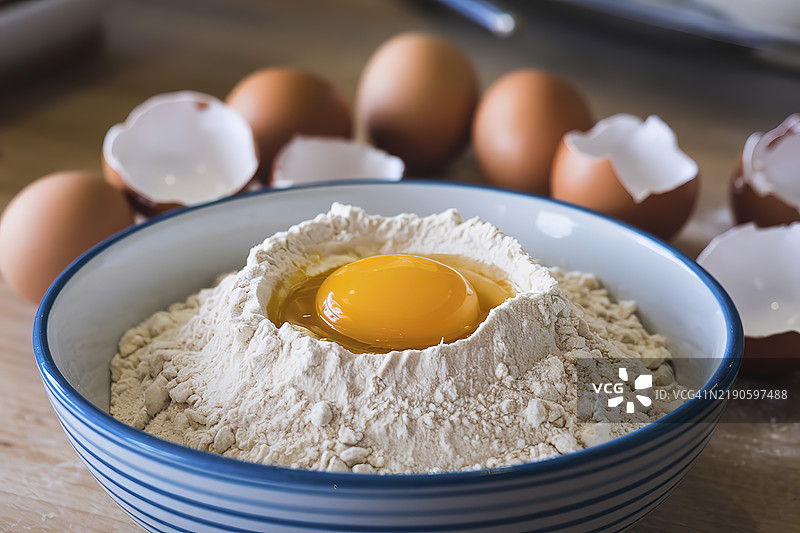 一碗面粉，上面放着一个破裂的蛋黄图片素材