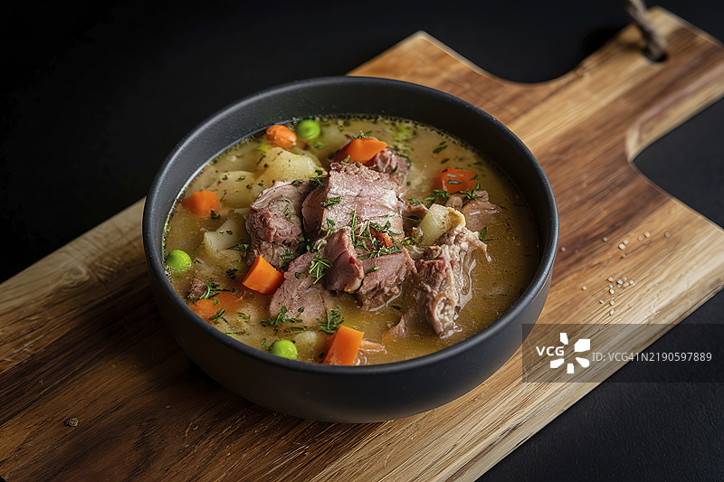 一碗丰盛的汤在黑色背景上图片素材