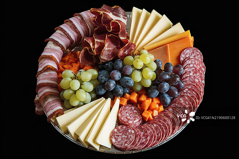 一盘包含培根、干肉、意大利香肠、奶酪和葡萄的开胃菜拼盘照片图片素材