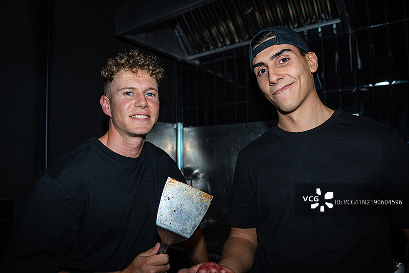 两位年轻厨师在餐厅厨房微笑图片素材