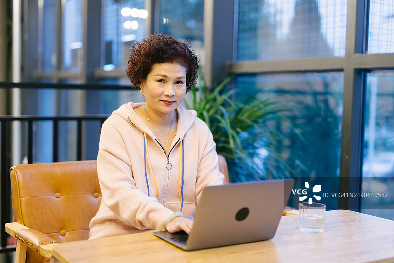 一位亚洲祖母在家使用笔记本电脑上网课图片素材