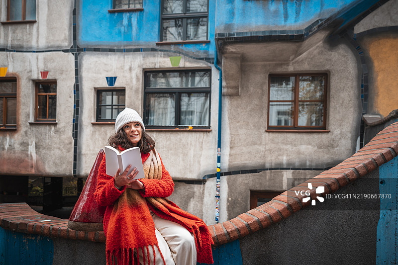 在奥地利维也纳五彩缤纷的亨德特瓦瑟区，一位女性正在阅读一本书。图片素材