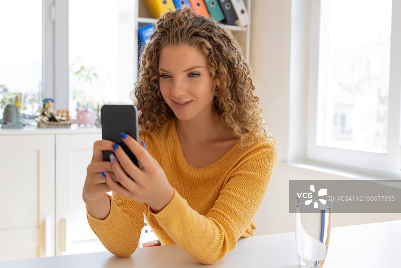 年轻女性坐着使用智能手机图片素材