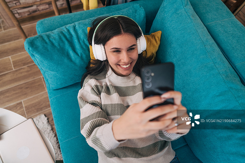 一位年轻女性戴着耳机享受音乐的自拍照图片素材