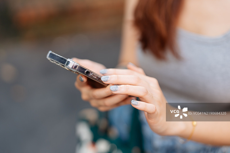 亚洲女性的手部特写，正在使用手机应用请求打车。图片素材