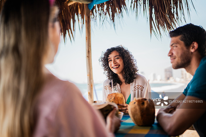 年轻女性在海滩餐厅与朋友交谈图片素材