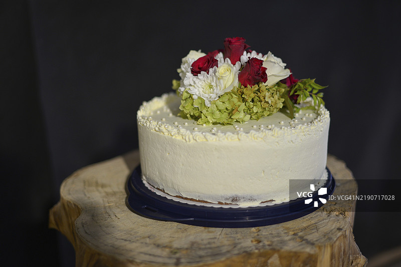 白色婚礼蛋糕，上面装饰着玫瑰花和其他花卉，放在木块上，德国巴伐利亚，欧洲图片素材