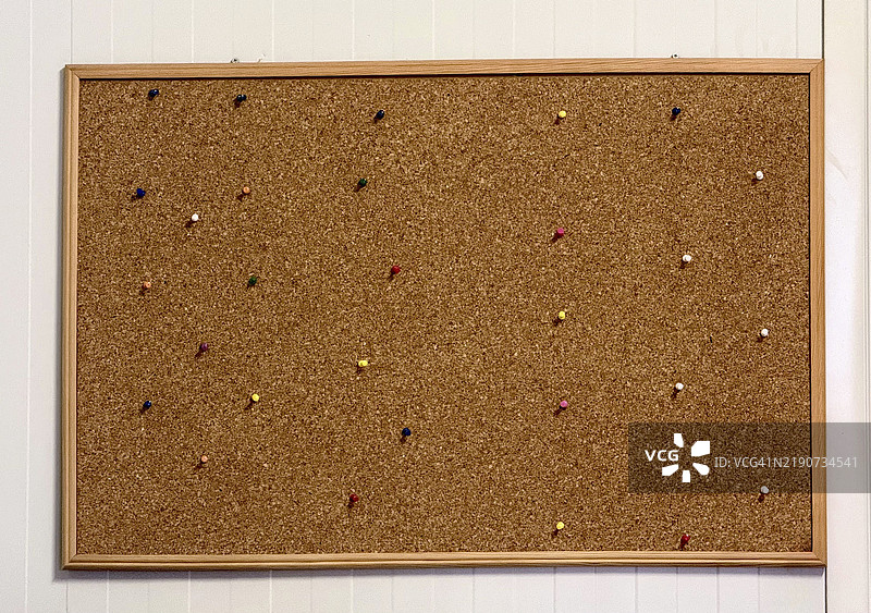 带有各种颜色图钉的软木公告板挂在墙上图片素材