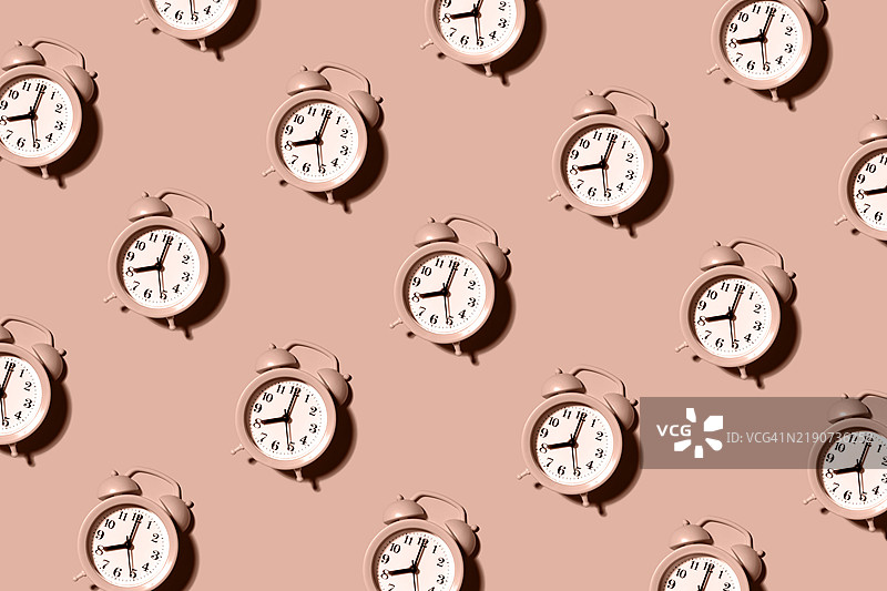 粉色柔和的背景上的闹钟。平铺。无缝图案图片素材