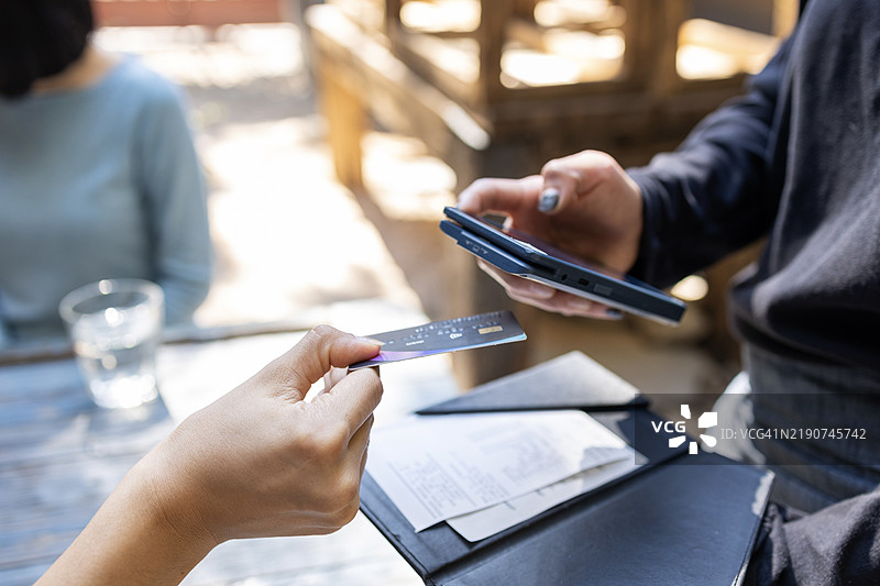女性在商店使用信用卡进行非接触式支付的特写镜头图片素材