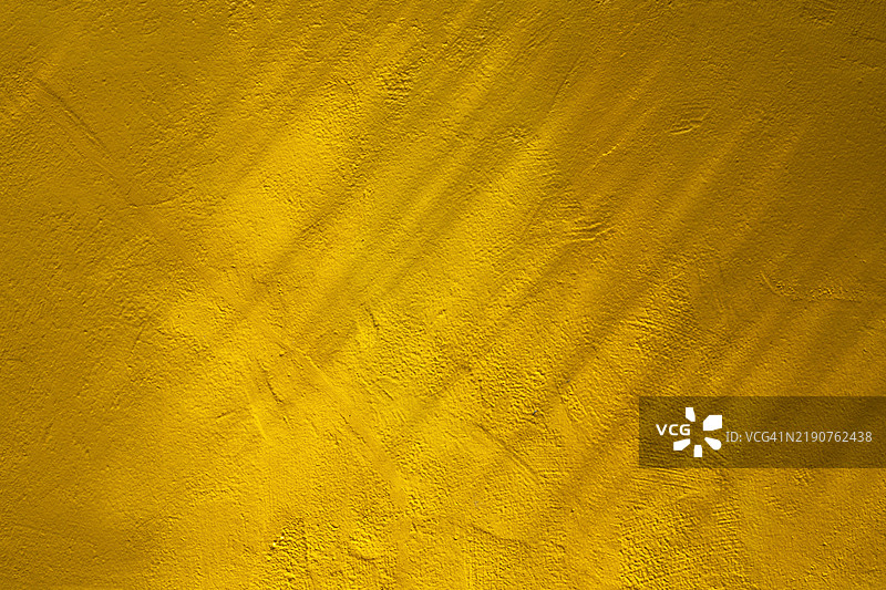 黄色混凝土墙壁背景上的抽象阴影。图片素材