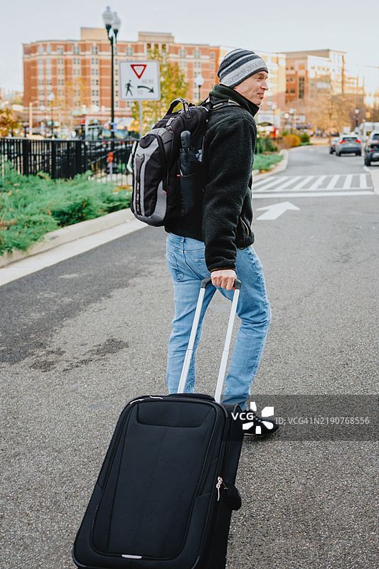 背着背包和行李箱的行走男子图片素材