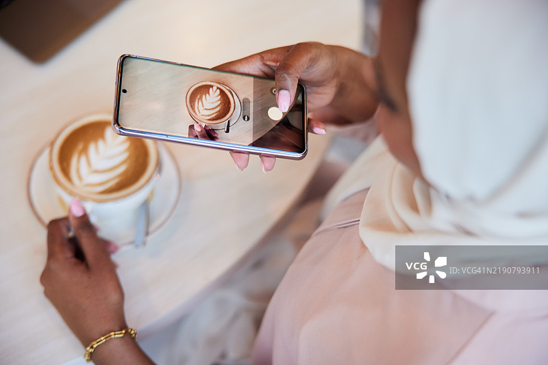 从一位女性在咖啡店拍摄她的卡布奇诺的视角来看，泡沫被完美捕捉。图片素材