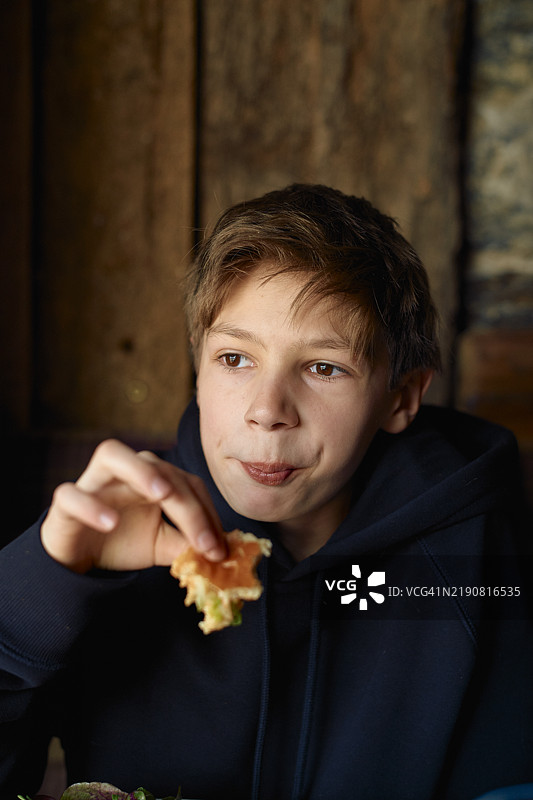 男孩在室内享受零食，神情沉思，爱丁堡，苏格兰图片素材