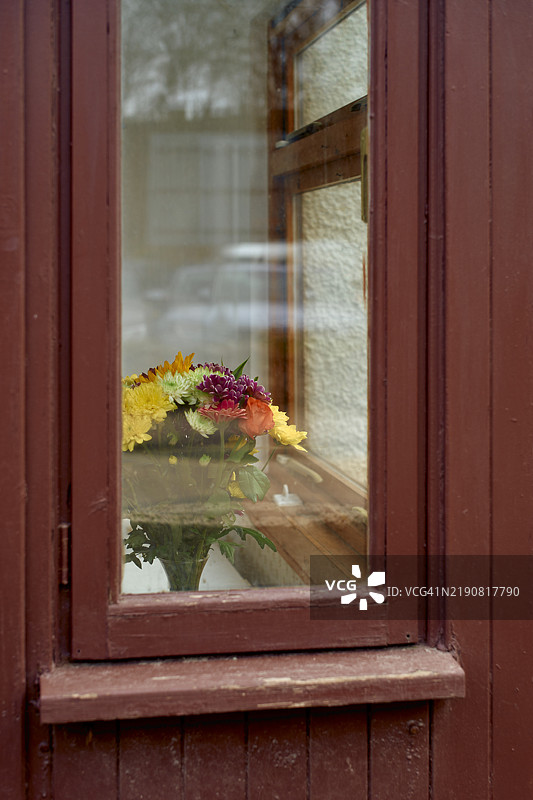 一个色彩斑斓的新鲜花束放在窗台上的花瓶里，窗后是一个木框窗户，苏格兰图片素材