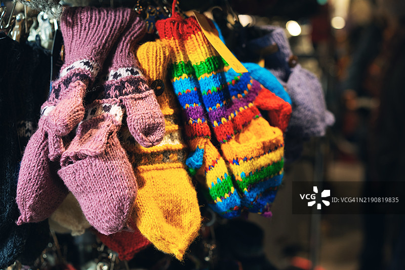 色彩斑斓的手工编织手套在温馨的市场摊位上展示图片素材
