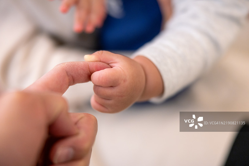 婴儿的小手握着母亲的手指特写图片素材
