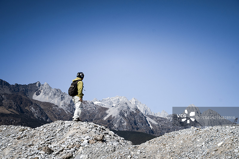 一个男孩在雪山下听音乐，享受美丽的风景图片素材