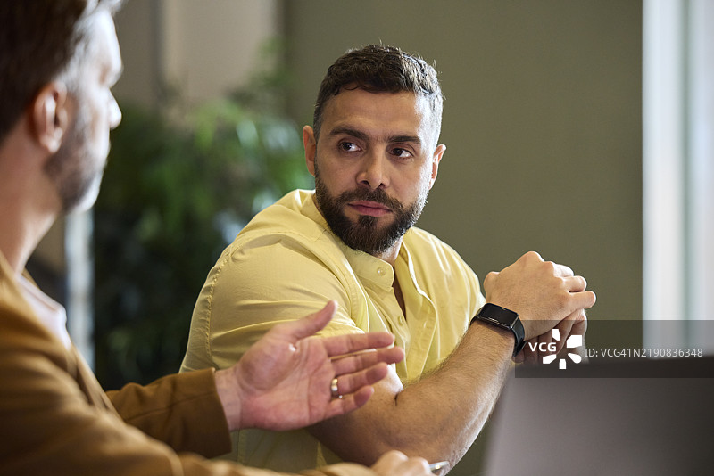 男性企业家在会议中倾听经理的发言图片素材